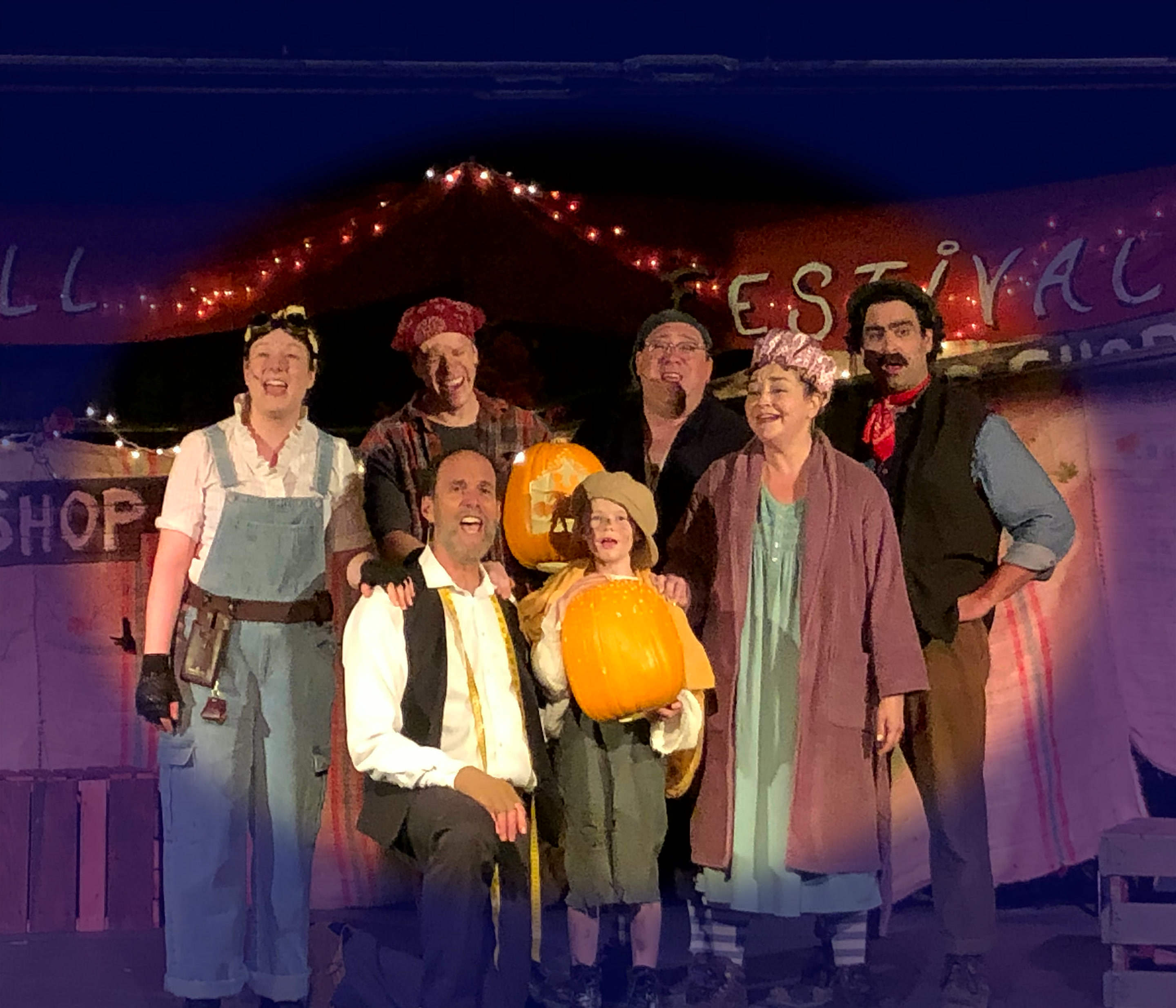 The cast of The Pumpkin Kid gathered onstage beneath the Fall Festival banner, the boy holding a pumpkin