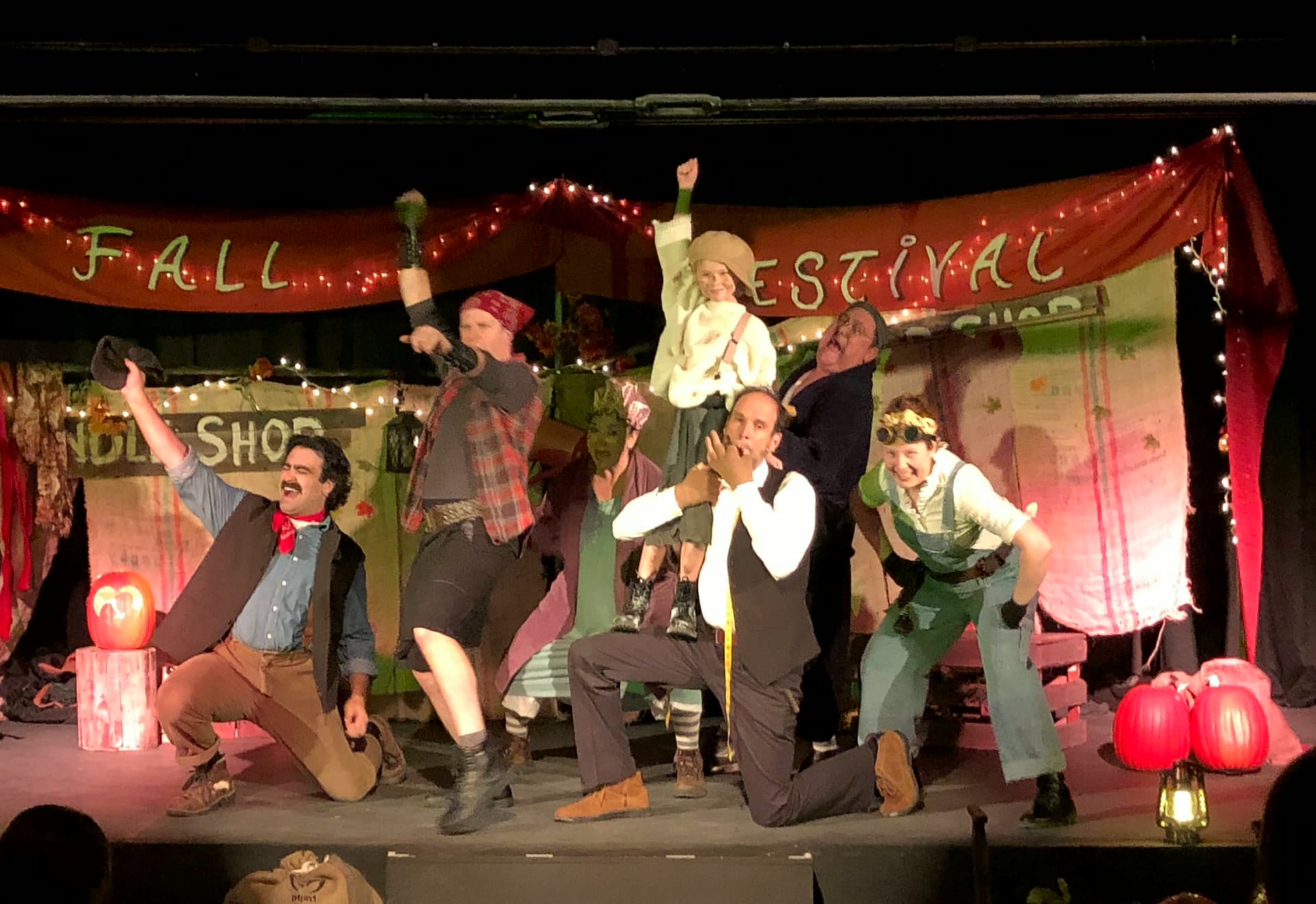 The full company performs The Blacksmith Song at the Fall Festival, the boy lifted above the ensemble