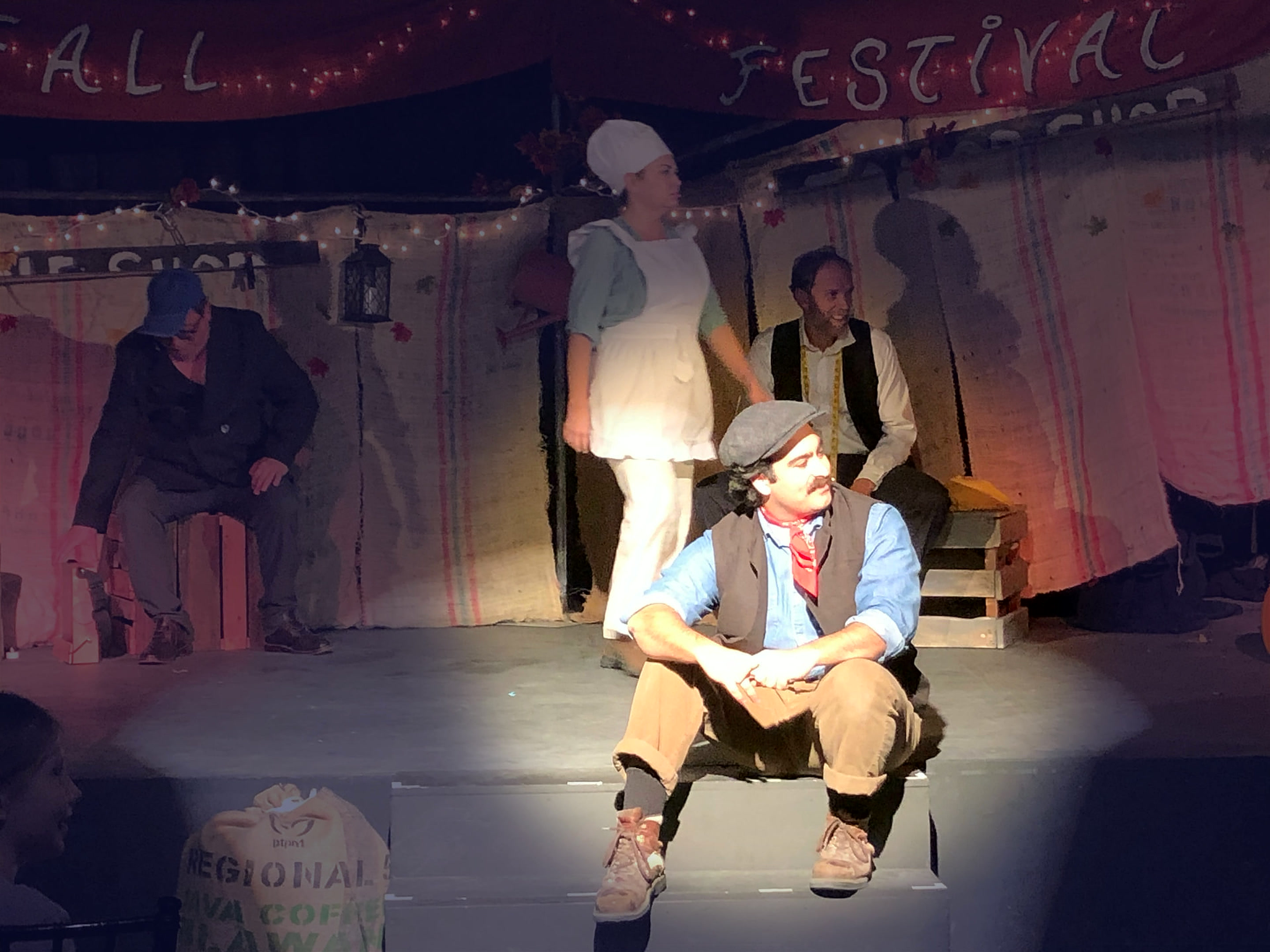 Villagers seated and standing on the Fall Festival set during a quiet scene